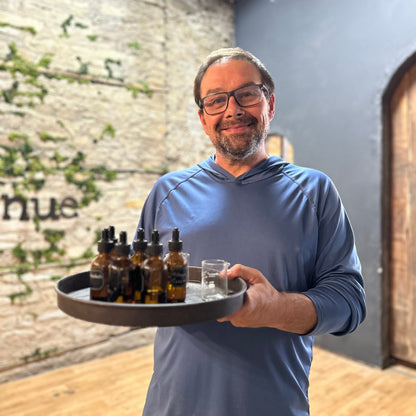 Man holding a tray with fragrance bottles for candle making in a studio setting