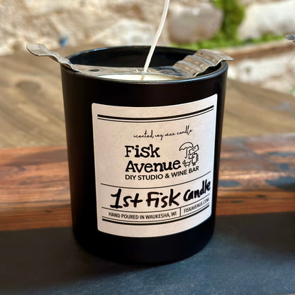 Black candle with a label on a wooden surface