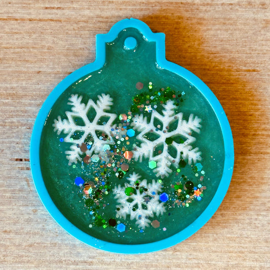 Decorative epoxy ornament with snowflakes and glitter on a wooden surface
