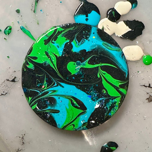 Colorful abstract painted design on a wooden magnet.