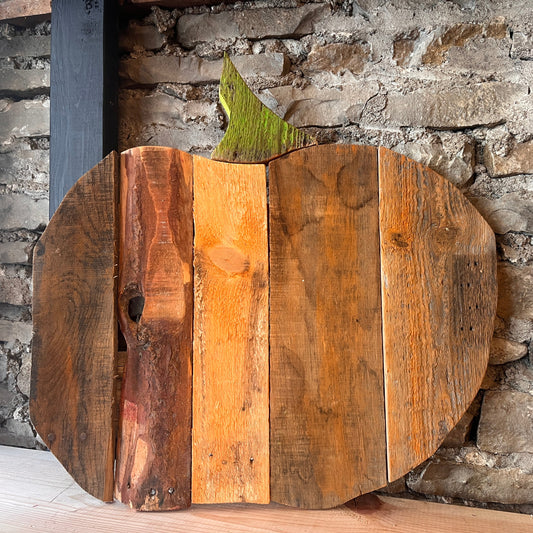 Wooden pumpkin decoration against a stone wall