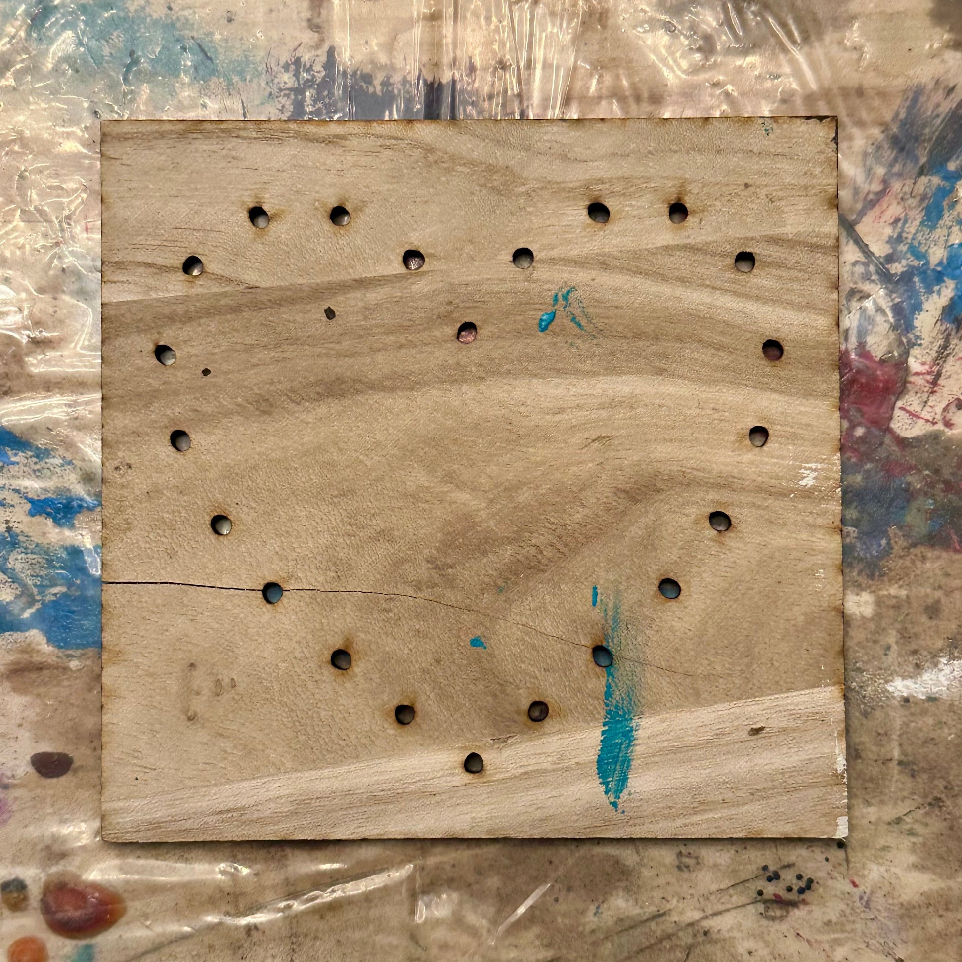 Wooden string art template with holes in a heart shape on a textured table background