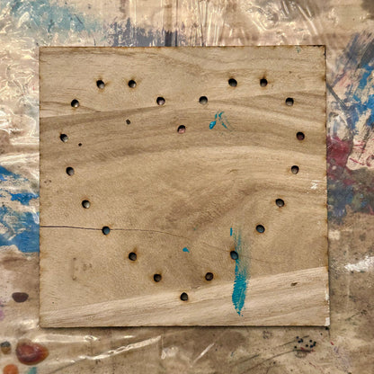 Wooden string art template with holes in a heart shape on a textured table background