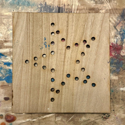 Wooden string art template with holes in a star shape on a textured table background