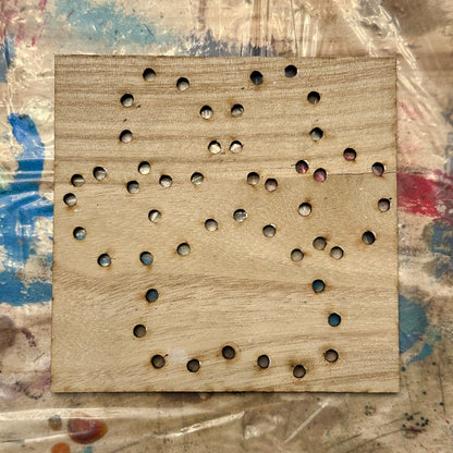 Wooden string art template with holes in a paw print shape on a textured table background
