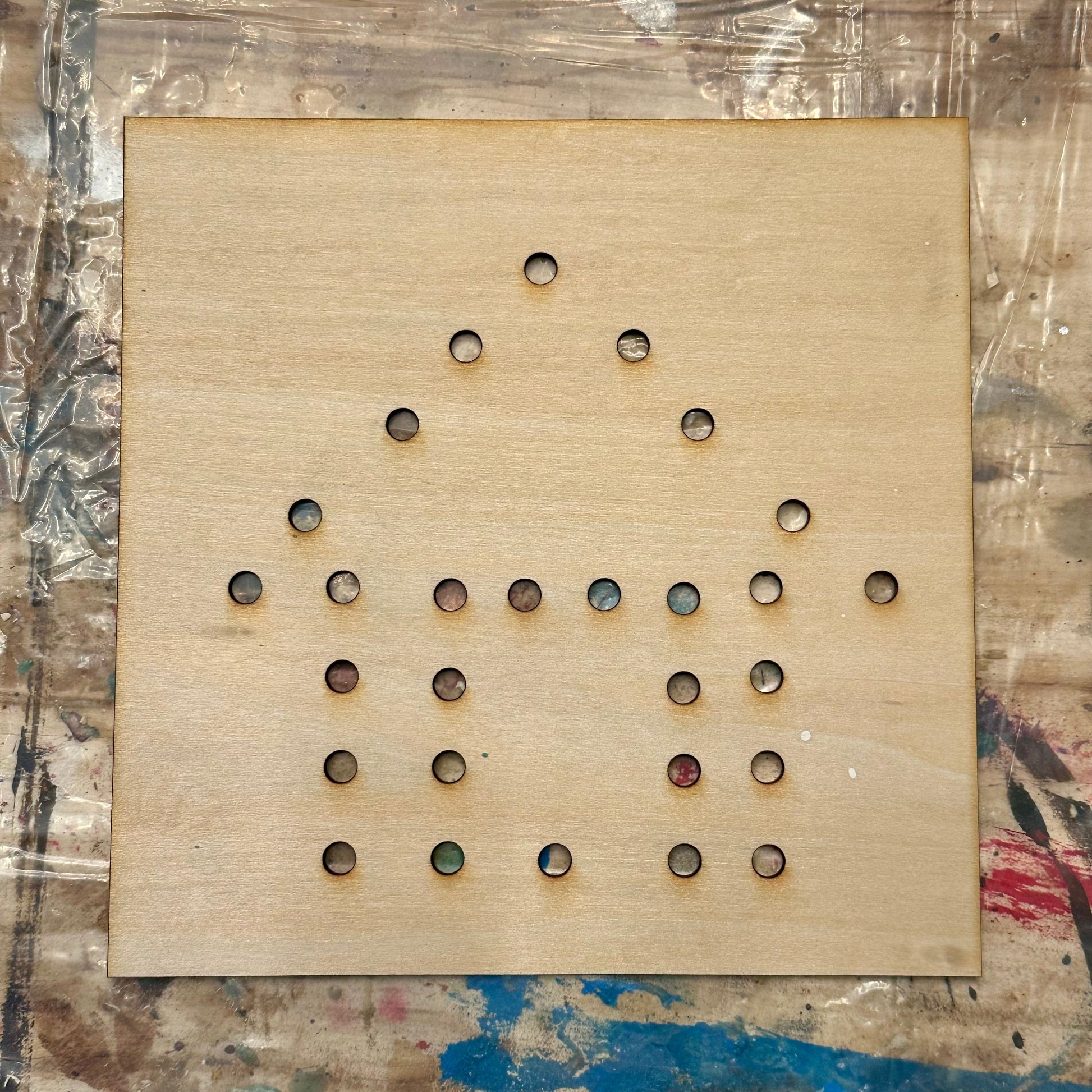 Wooden string art template with holes in a house shape on a textured table background