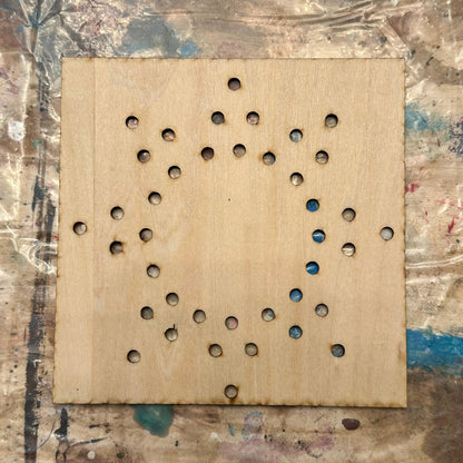Wooden string art template with holes in a sun shape on a textured table background