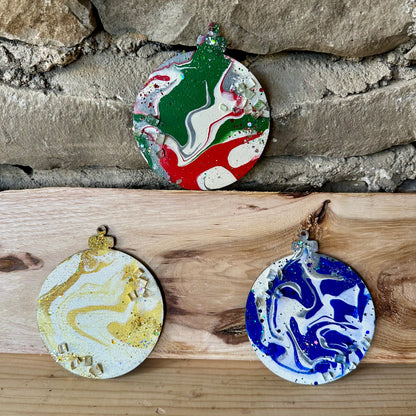 Three marbled ornaments on a wooden surface with a stone wall background.