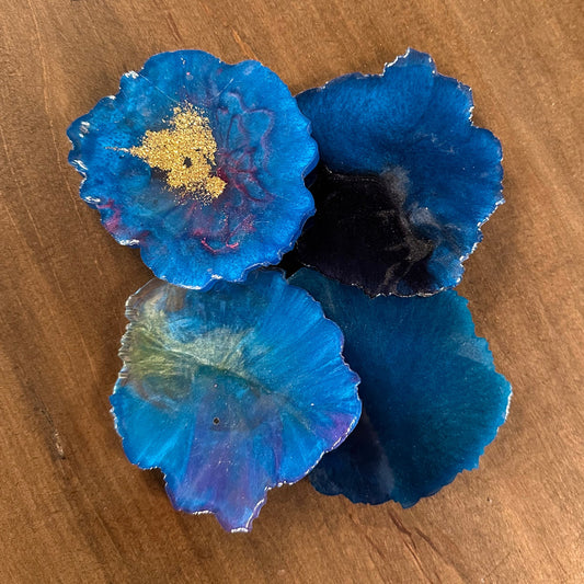 Blue epoxy coasters with gold center on a wooden surface