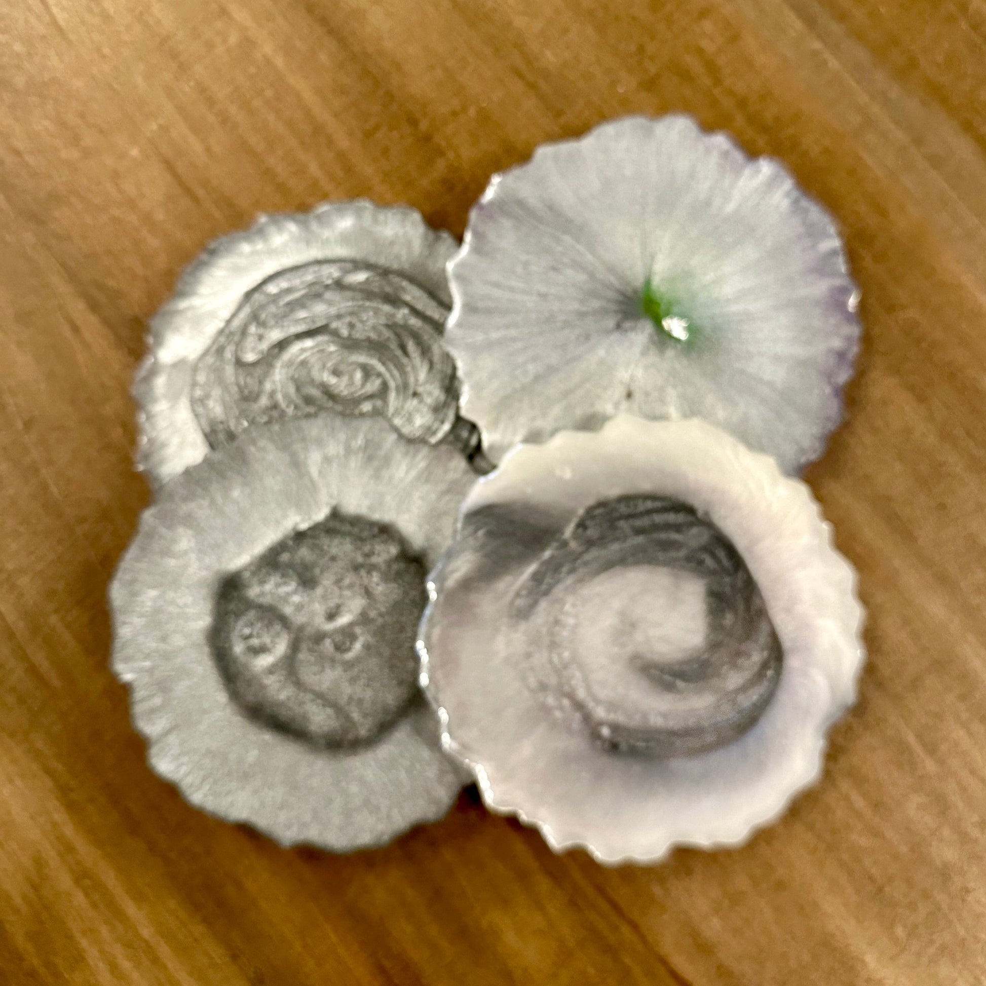 Three silver epoxy coasters on a wooden surface