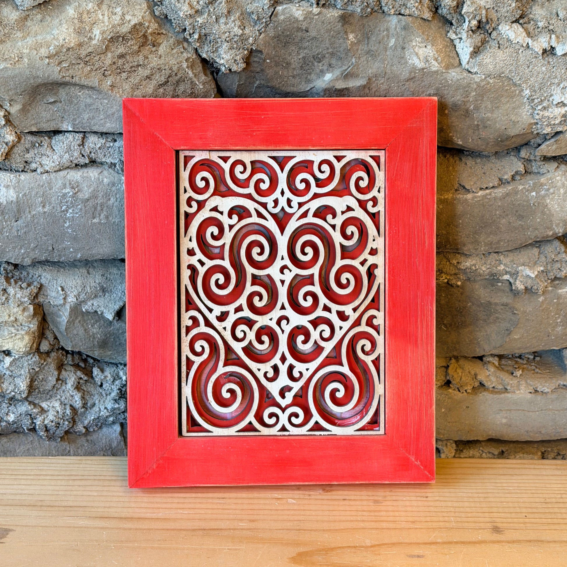 Decorative red frame with intricate heart patterns against a stone wall background