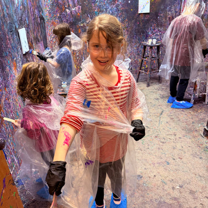 Child in an art studio with paint splatters on a wall and floor