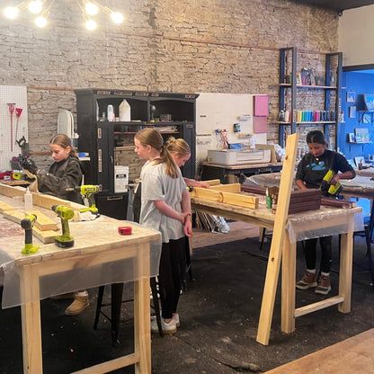 Workshop with tables, tools, and people in a casual setting.