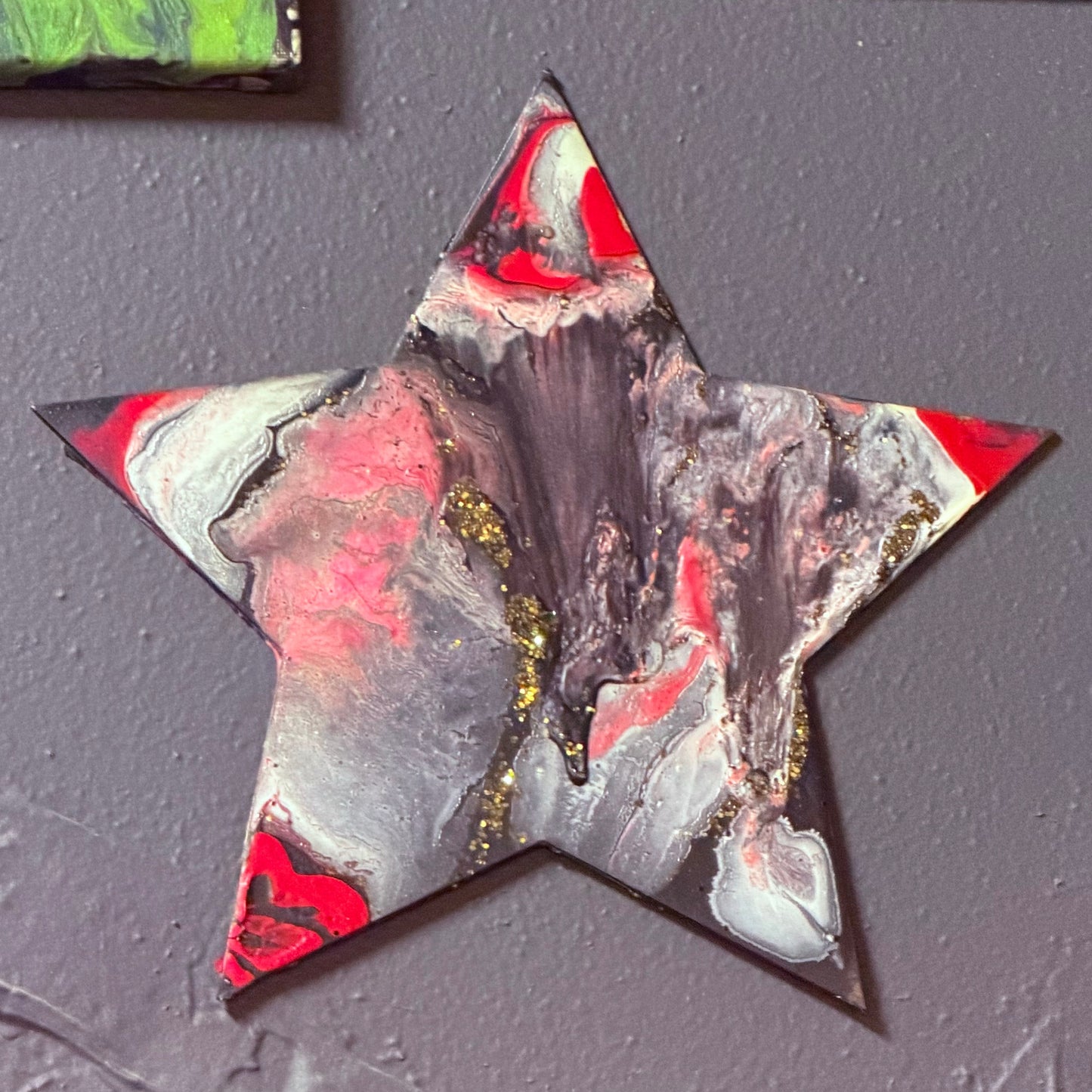 Artistic star-shaped decoration on a black wall with abstract paintings in the background.