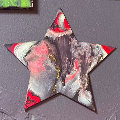 Artistic star-shaped decoration on a black wall with abstract paintings in the background.
