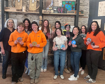 Group of people posing together in a studio and holding epoxy crafts.