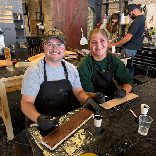 Two people working on a wooden pet hook rack project in a workshop.