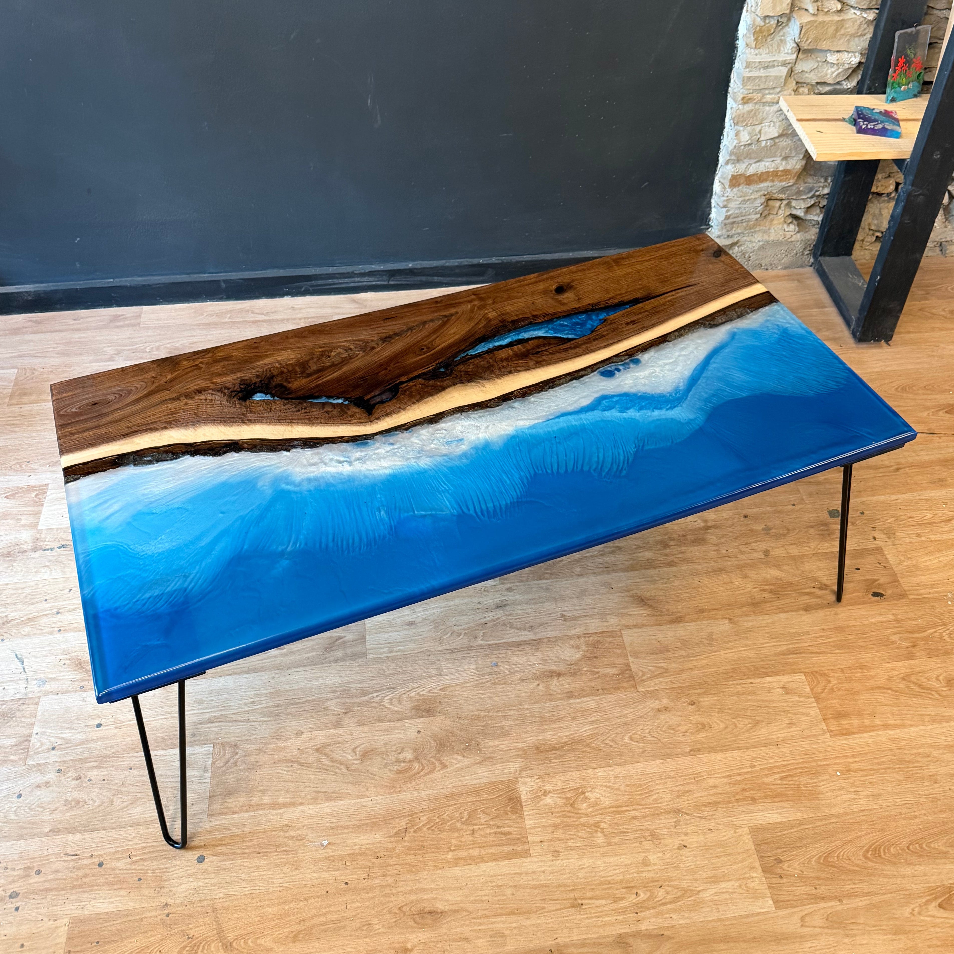 Coffee table with blue resin waves design on a wooden floor