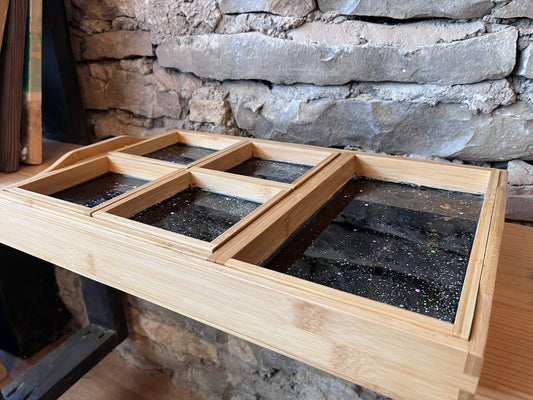 7-piece wooden charcuterie tray set with compartments and an epoxy galaxy design against a stone wall.