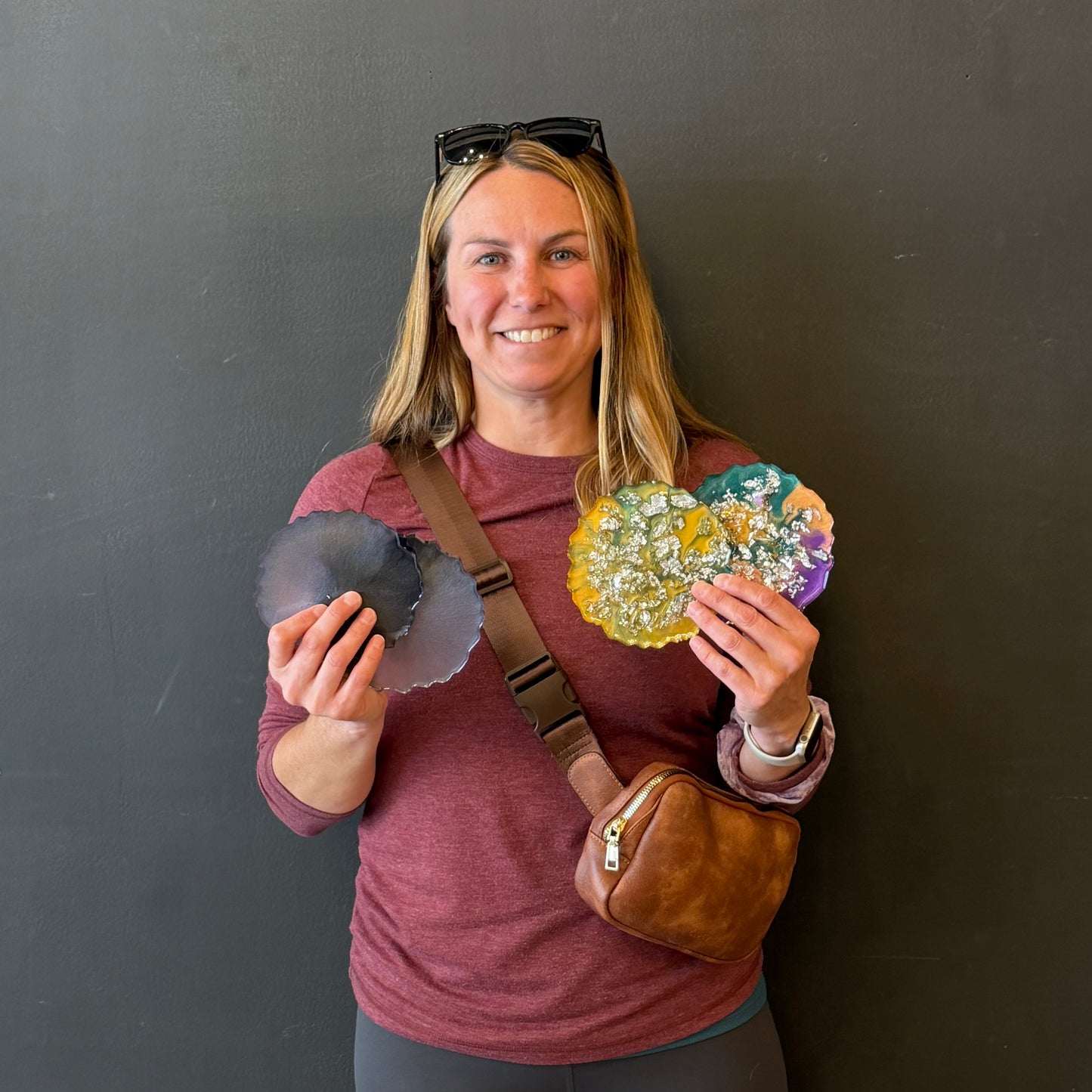 Person holding epoxy coasters on a plain background