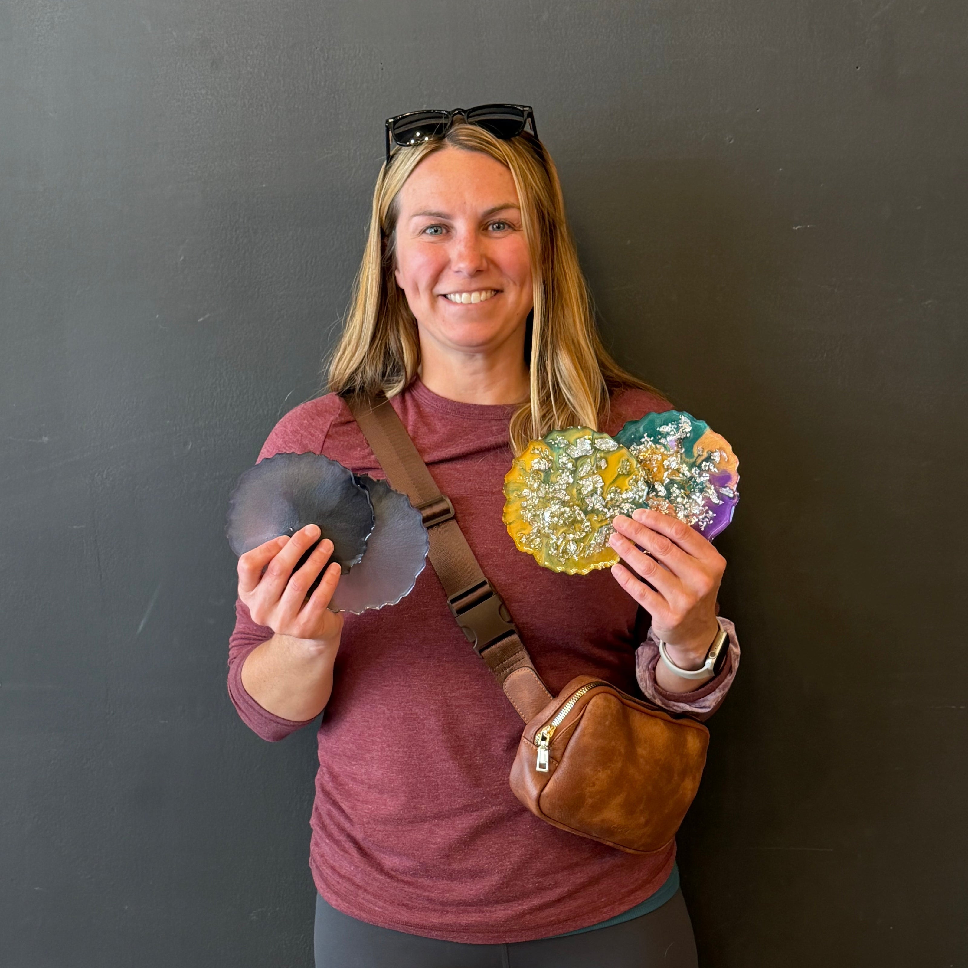 Person holding epoxy coasters on a plain background