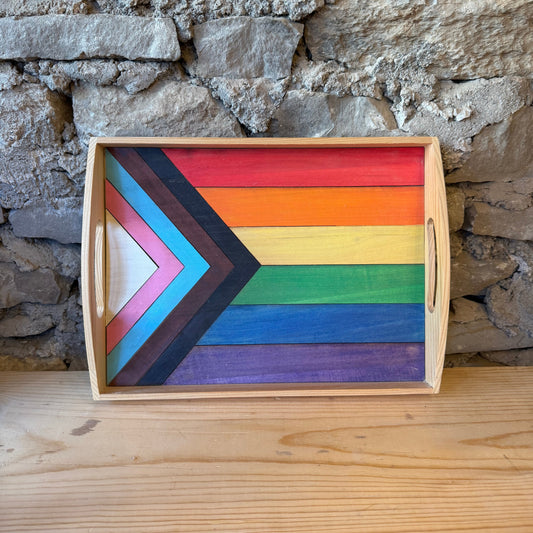Wooden tray with rainbow pride flag design on a stone wall background