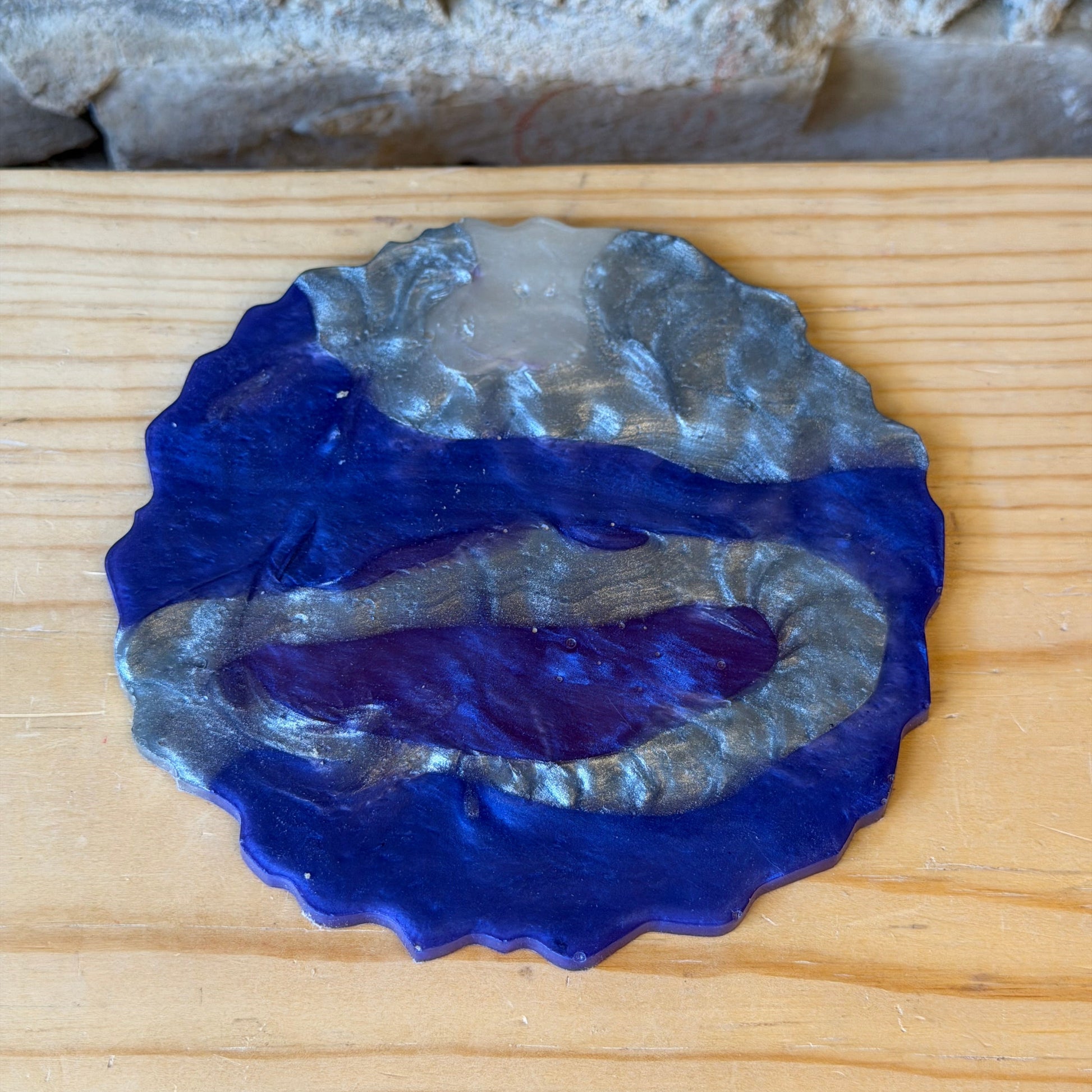 Decorative epoxy coaster with silver and purple colors on a wooden surface