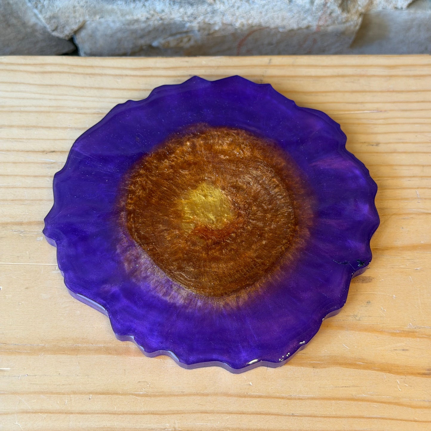 Purple epoxy coaster with golden center on a wooden surface