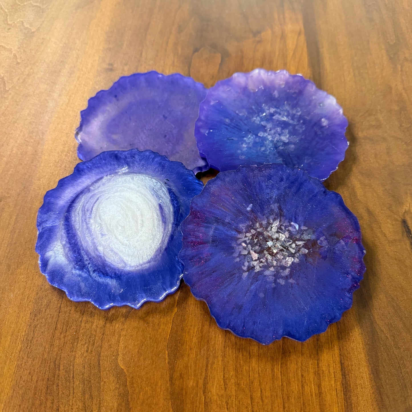 Four blue and silver epoxy coasters on a wooden table