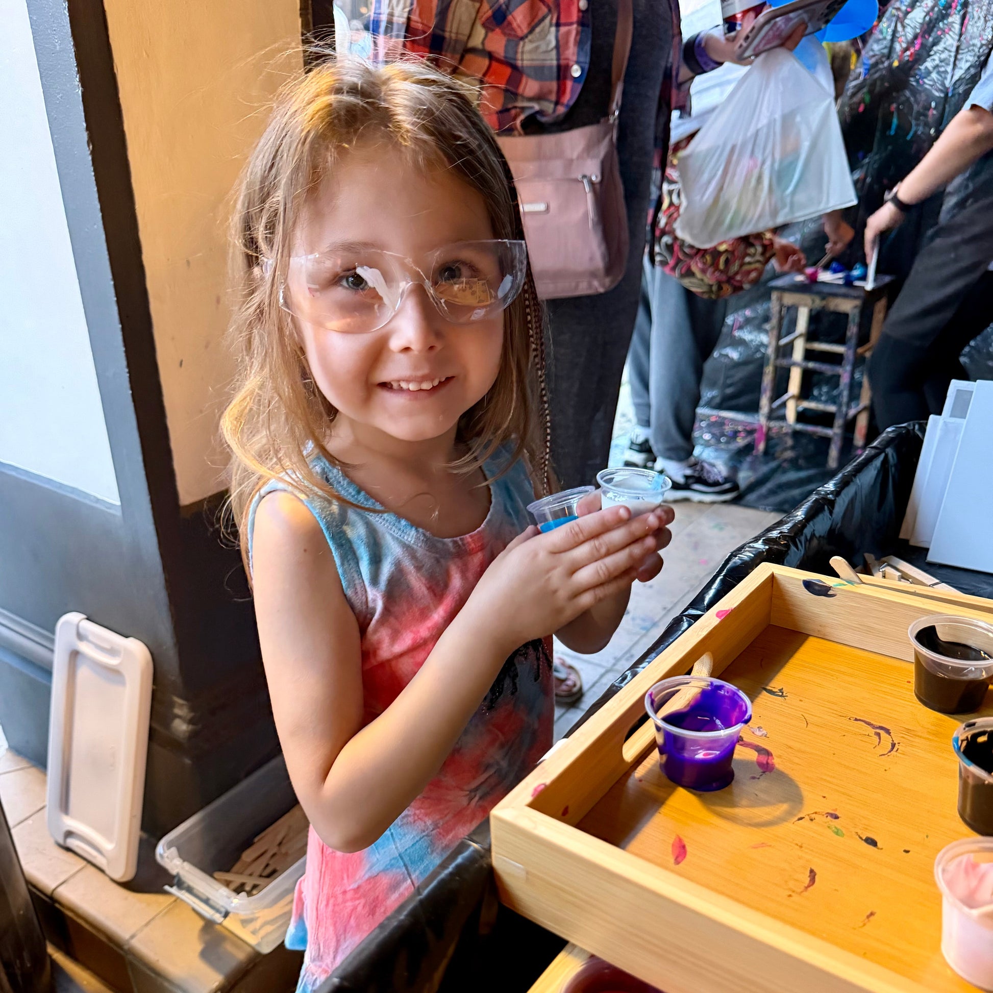 Young girl wearing safety goggles at a craft station with paint.