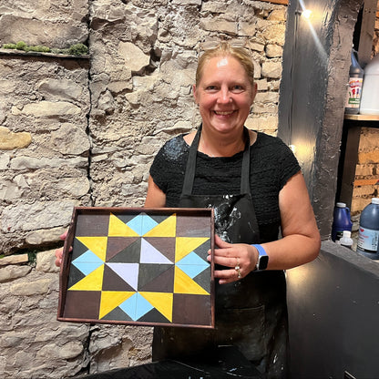 Person holding a geometric patterned tray against a stone wall.