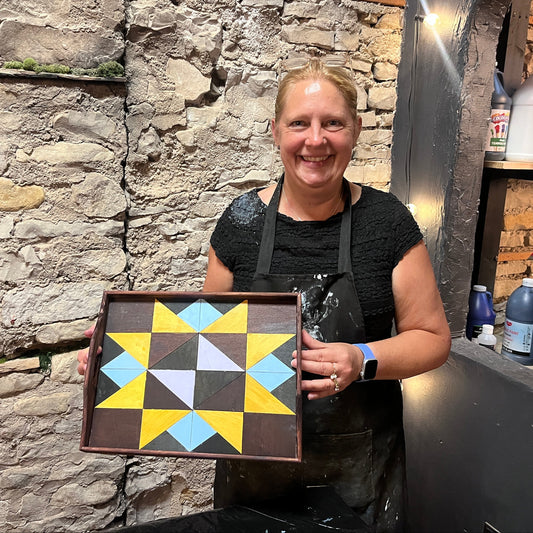 Person holding a geometric patterned tray against a stone wall.
