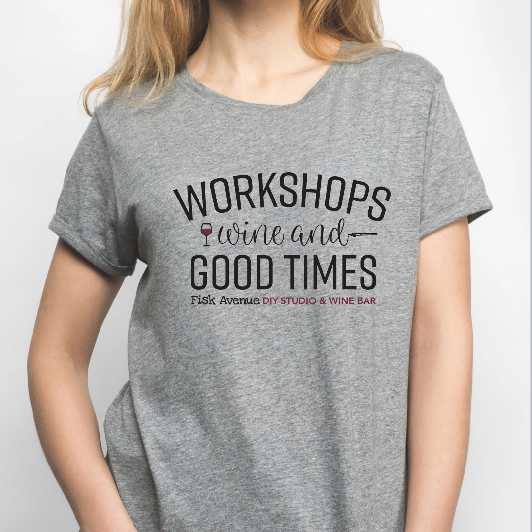 Person wearing a gray t-shirt with text about workshops, wine, and good times.