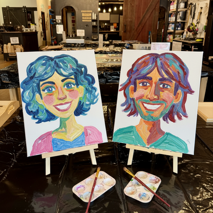 Two colorful portrait paintings on canvas displayed on small easels in a workshop or studio setting, with paint palettes and brushes in front.