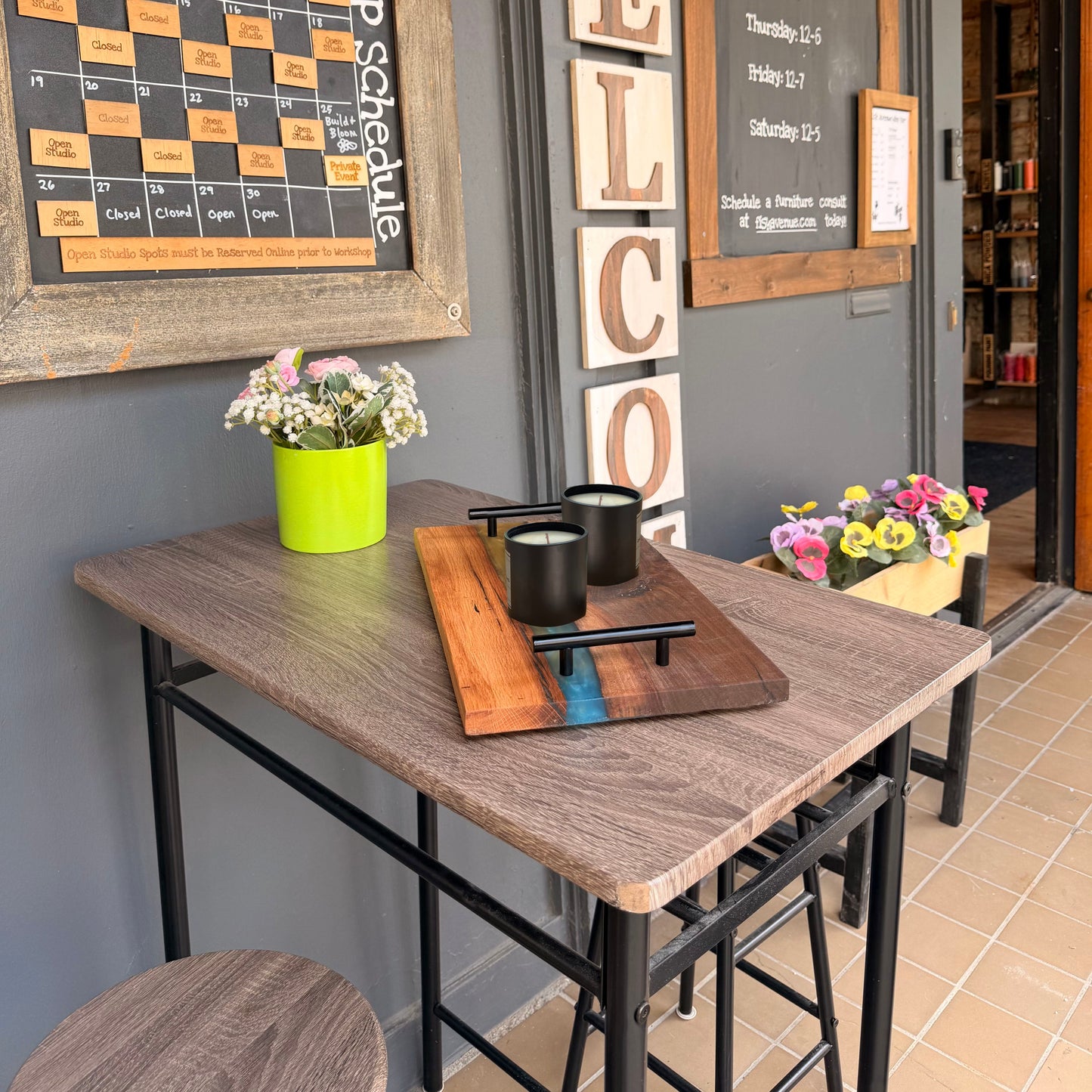 Patio area with a wooden table, stools, and candles on a gray wall.