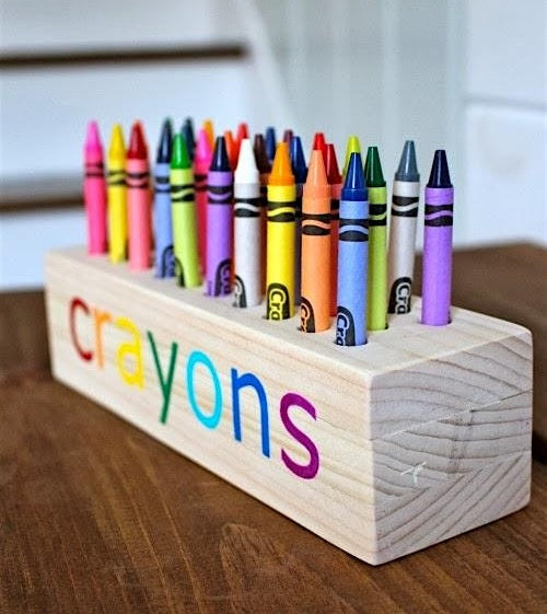 Colorful crayons in a wooden holder on a wooden surface