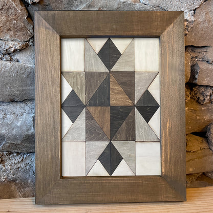 Wooden framed artwork with geometric pattern on a stone wall background