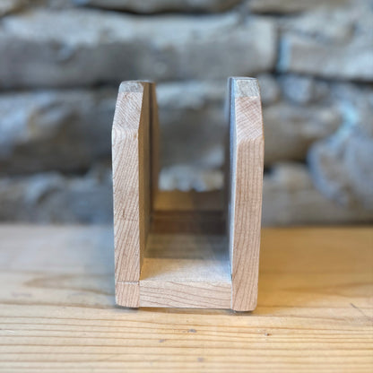 Wooden napkin holder on a wooden surface with a stone wall background