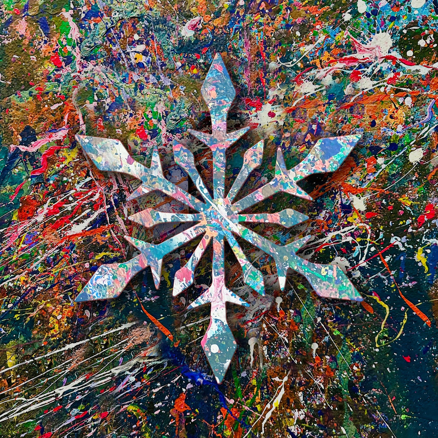 Wooden cutout of a splatter painted snowflake on a colorful wall.